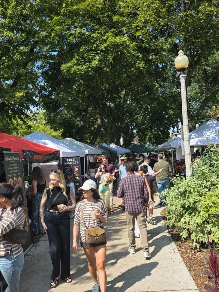 Busy market scene with vendor tents and shoppers enjoying fresh produce